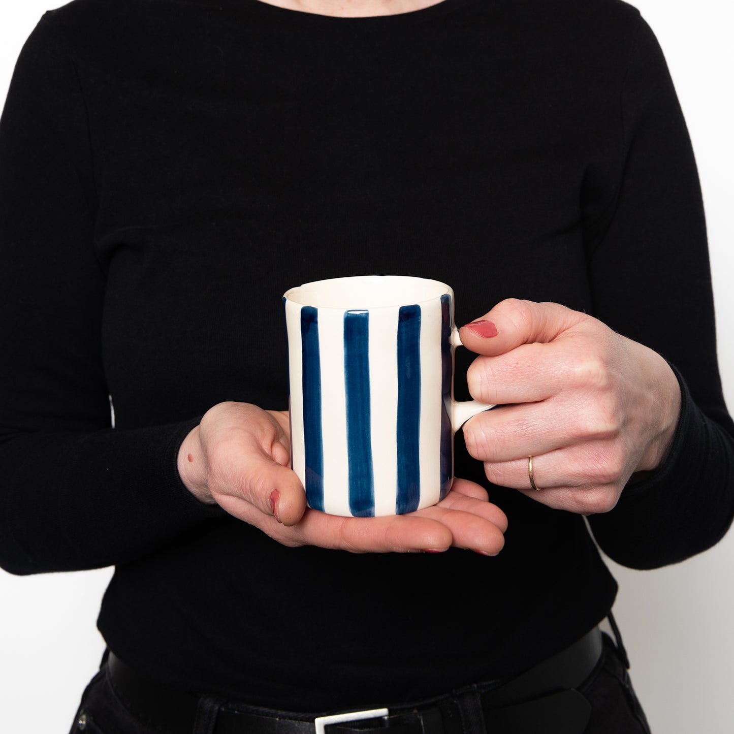 The mug being held against black clothing to show size