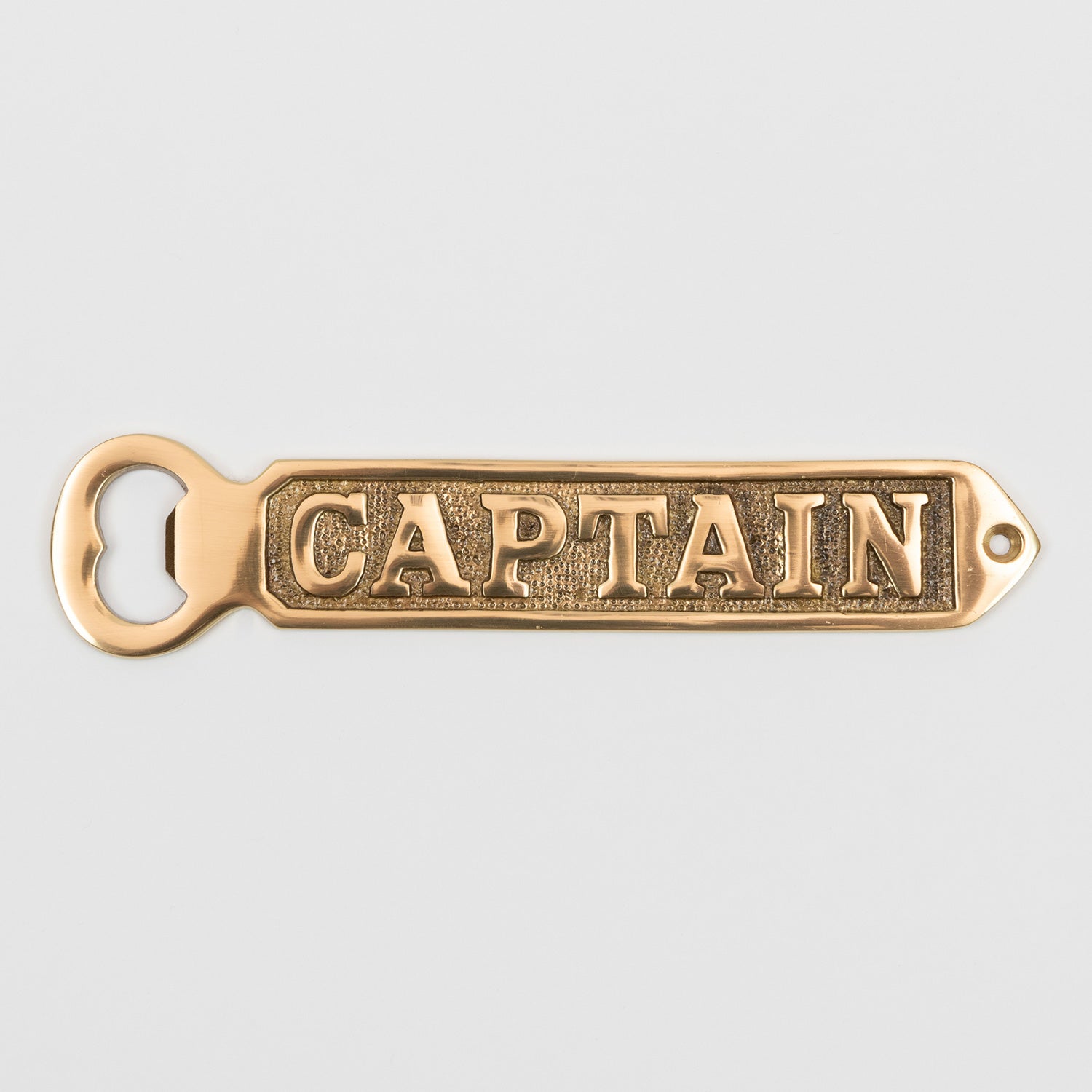 A solid brass bottle opener with 'Captain' written on it. Photographed on a white background.
