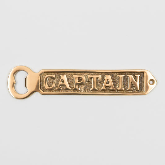 A solid brass bottle opener with 'Captain' written on it. Photographed on a white background.