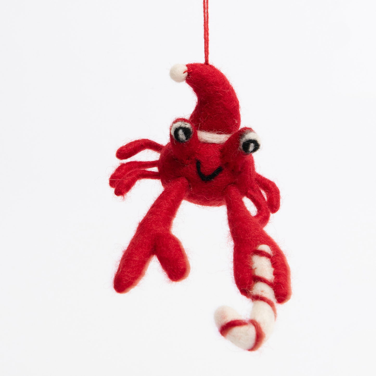 A Christmas crab decoration pictured on a white background. The felt crab is red and is wearing a Christmas hat.