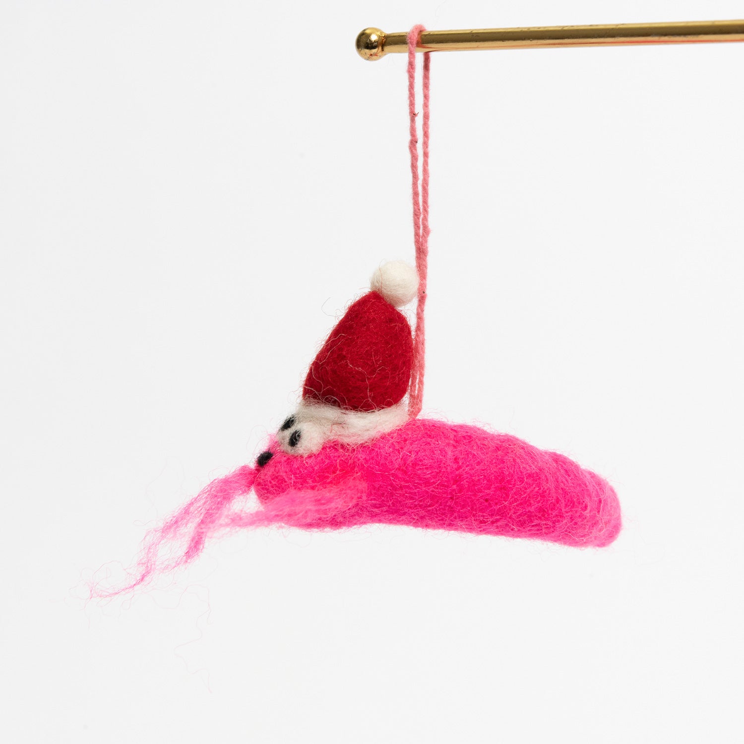 A Christmas decoration hanging on a metal rod on a white background. The decoration is a festive pink prawn wearing a Christmas hat.