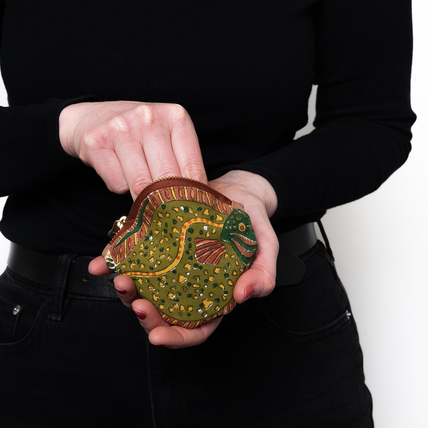 Green, brown and yellow purse with flat fish design, being unzipped and reached into