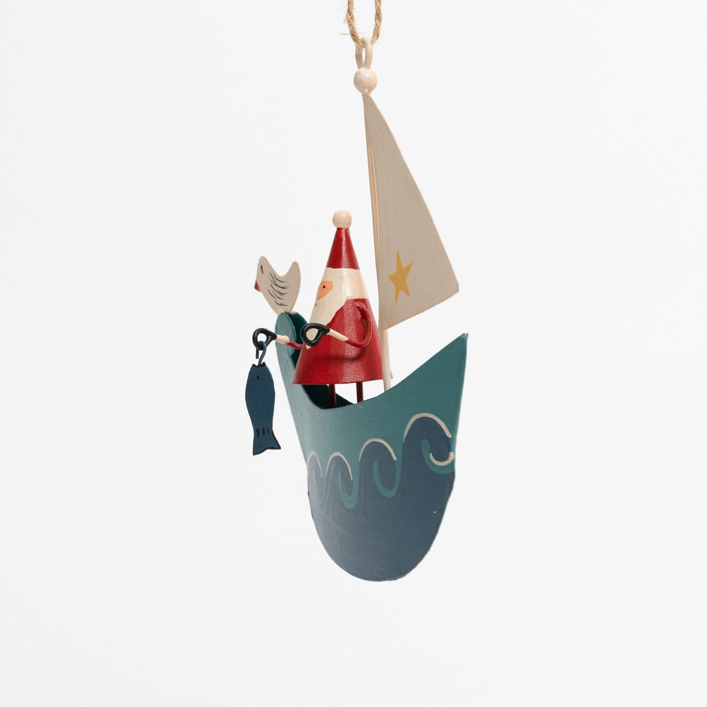 A Christmas decoration pictured on a white background. The decoration is Santa standing on a blue sailboat with blue waves lapping up around it. There is a seagull sat on the front of the ship, and Santa is holding a fish.
