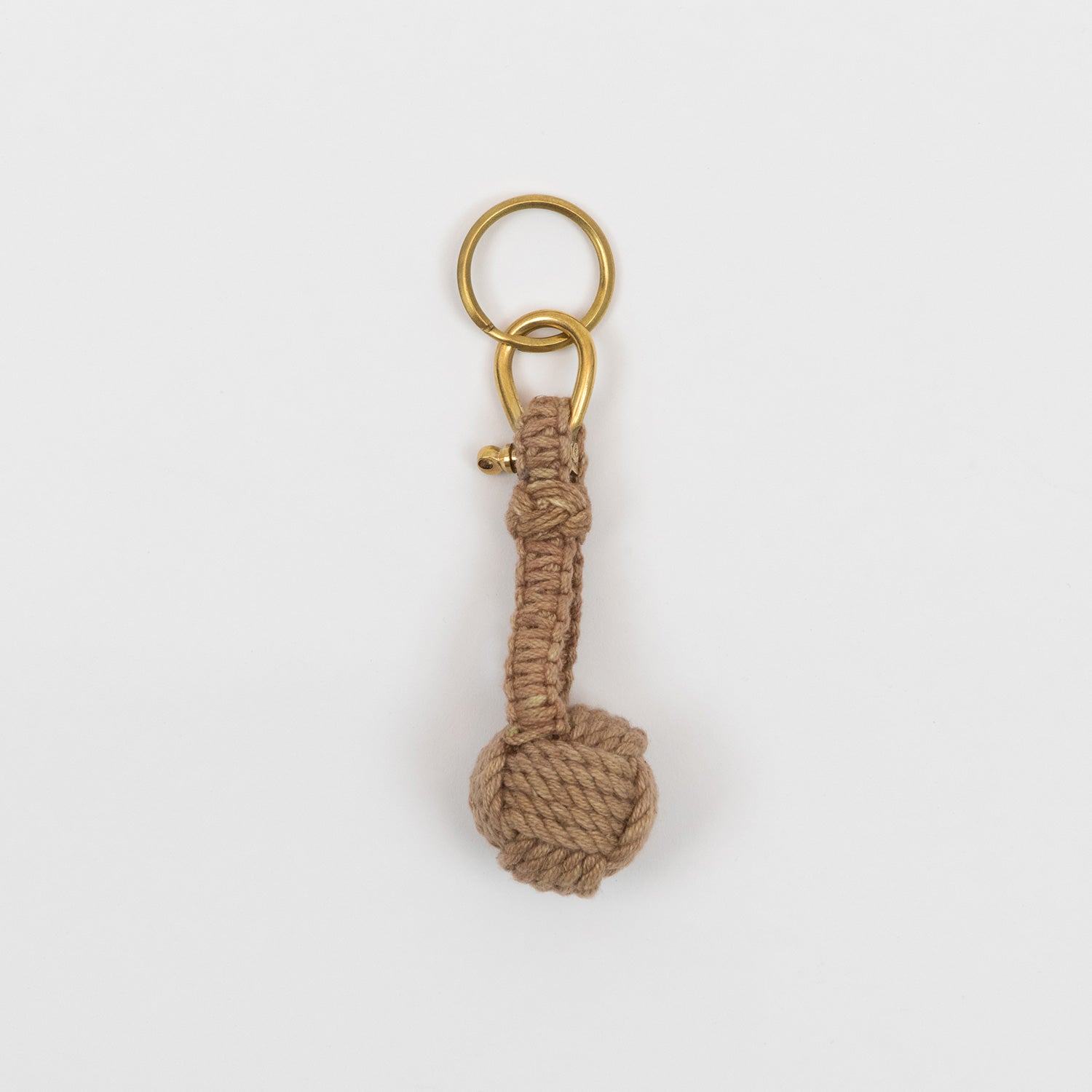 A monkey fish rope keyring, with brown rope and a gold ring, on a white background.