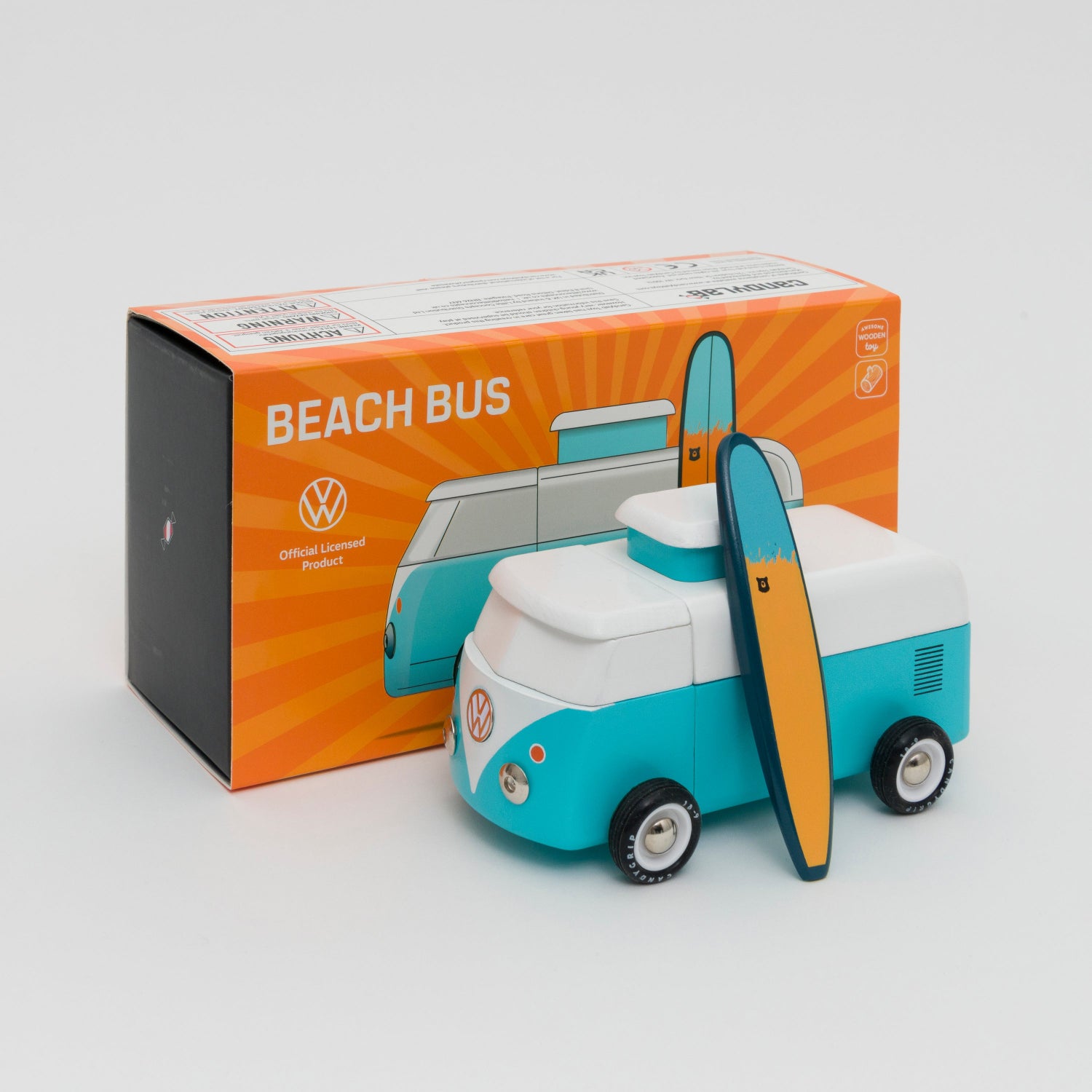 Shot of turquoise and white VW camper van with wooden surfboard leaning against the van. Shot in front of its box