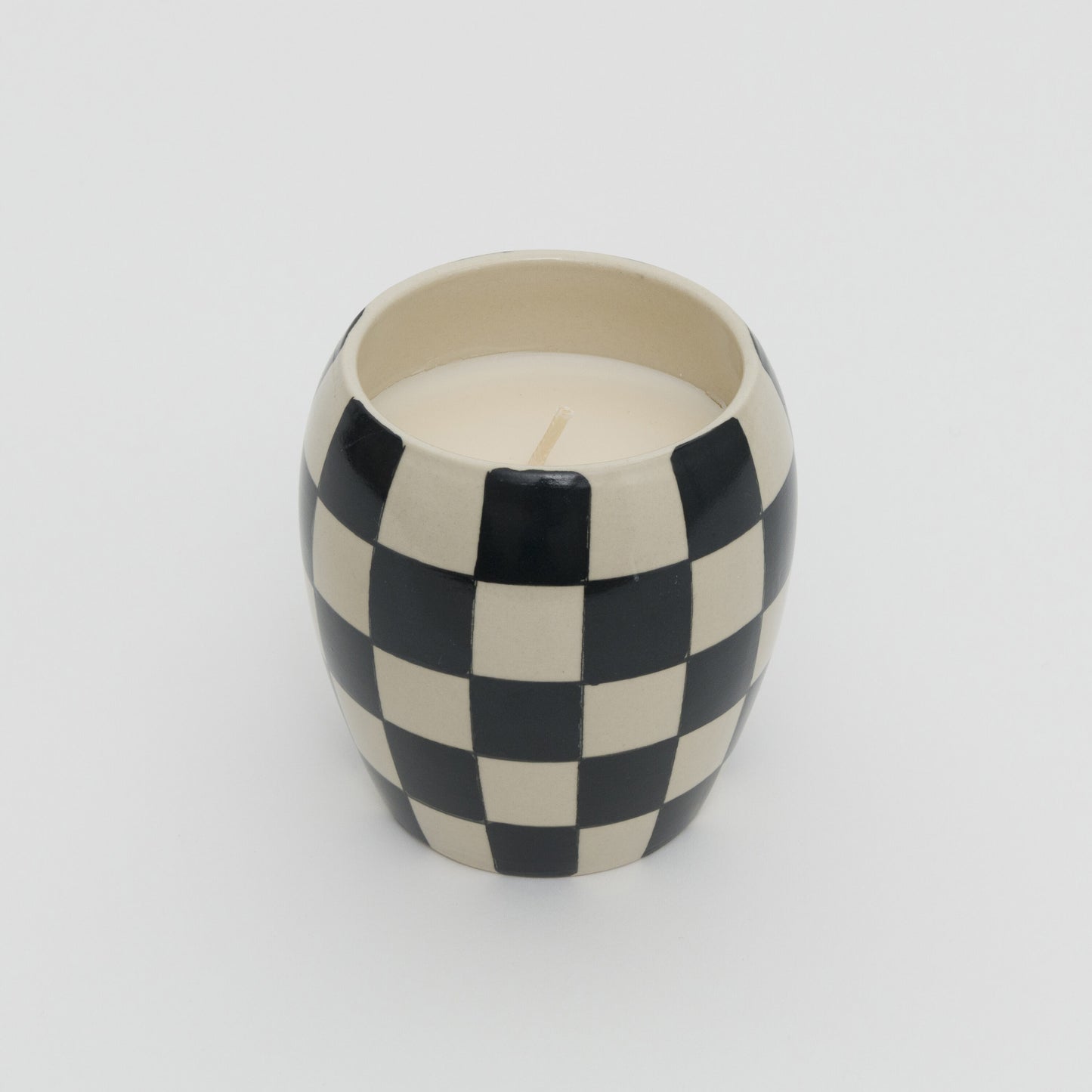 Black and white checkerboard design ceramic pot with white candle.