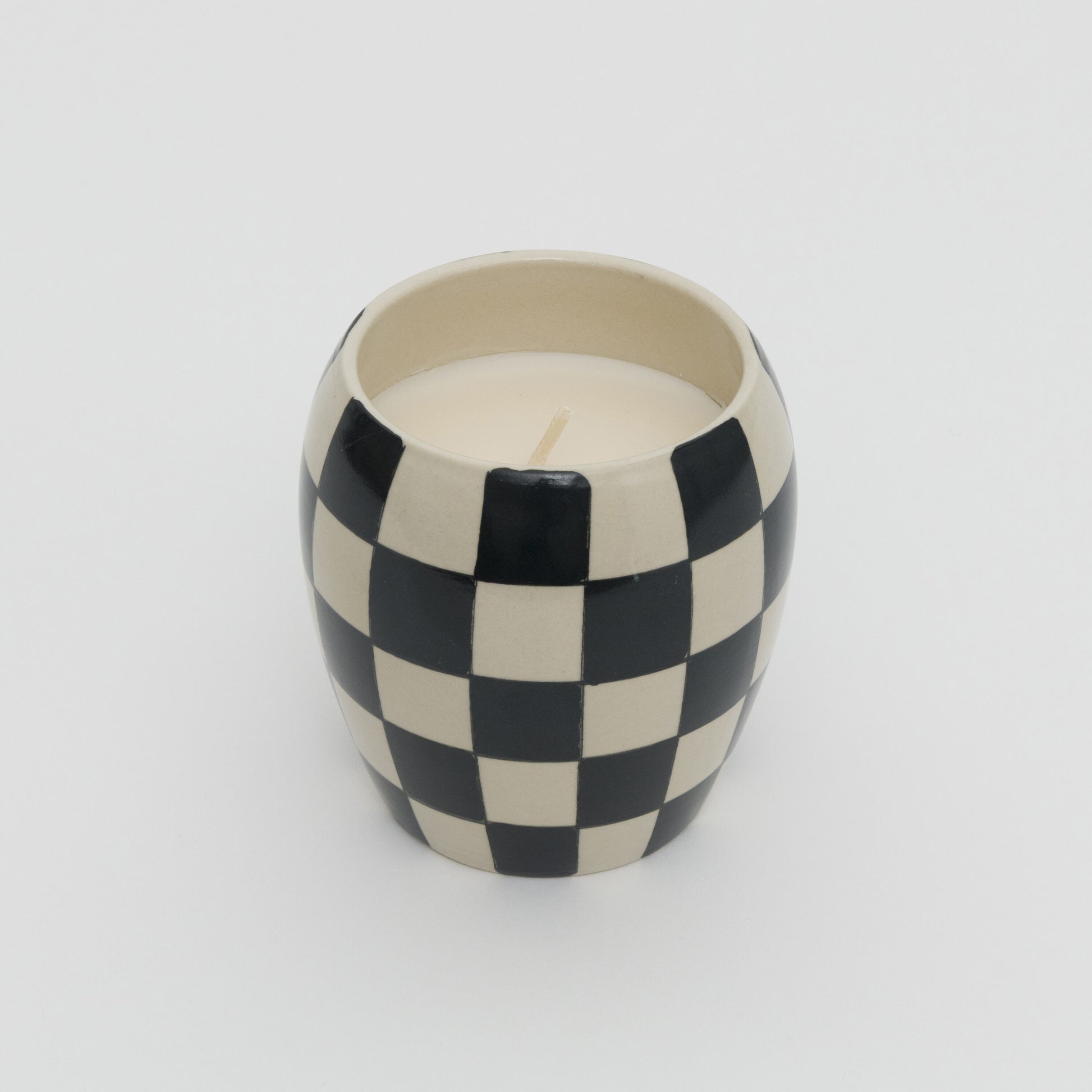 Black and white checkerboard design ceramic pot with white candle.