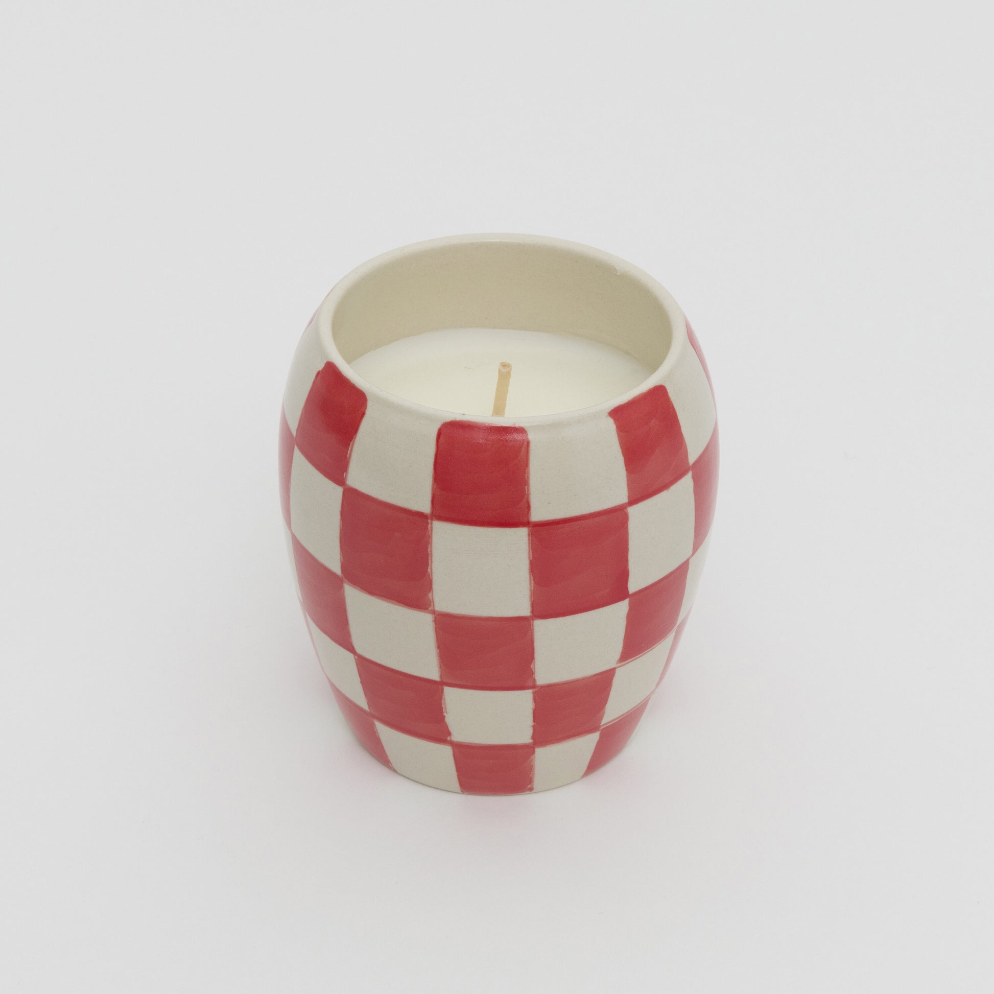 Red and white checkerboard design ceramic pot with white candle.