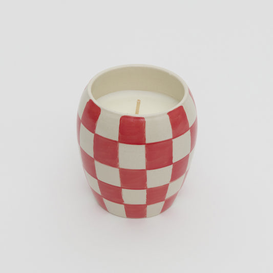 Red and white checkerboard design ceramic pot with white candle.