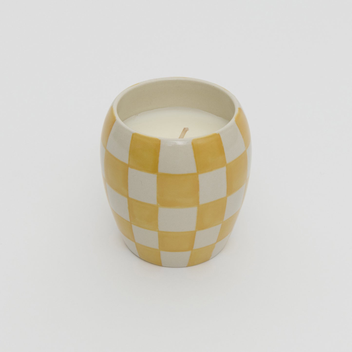 Yellow and white checkerboard design ceramic pot with white candle.