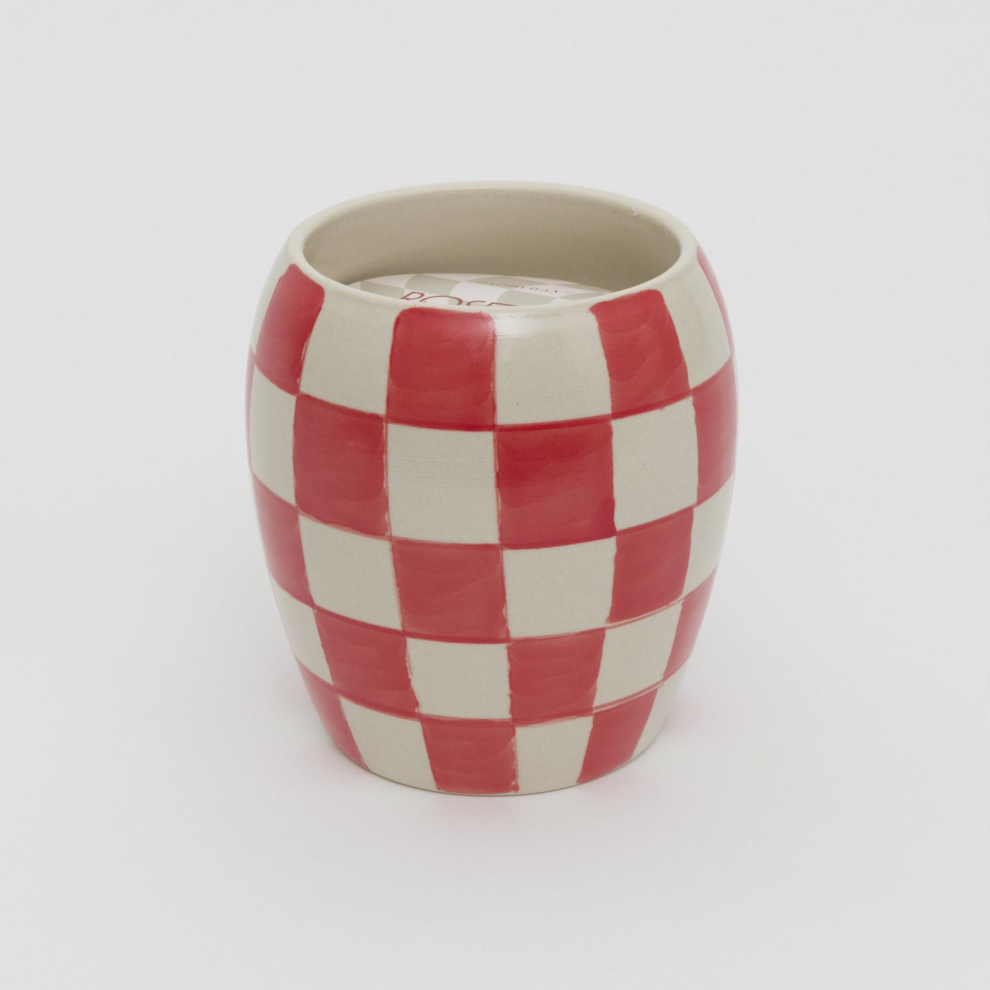 Red and white checkerboard design ceramic pot with white candle.