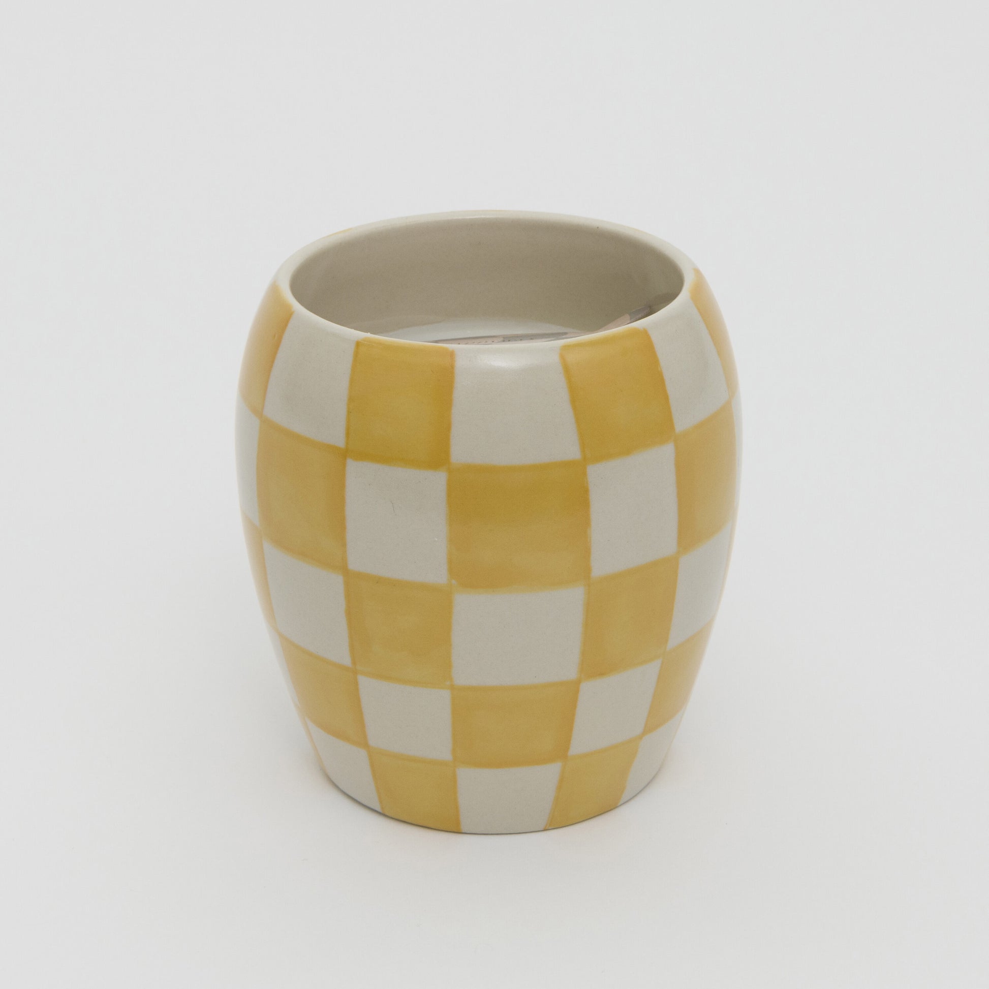 Yellow and white checkerboard design ceramic pot with white candle.