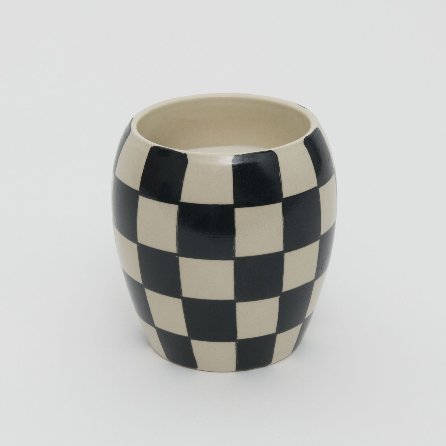 Black and white checkerboard design ceramic pot with white candle.