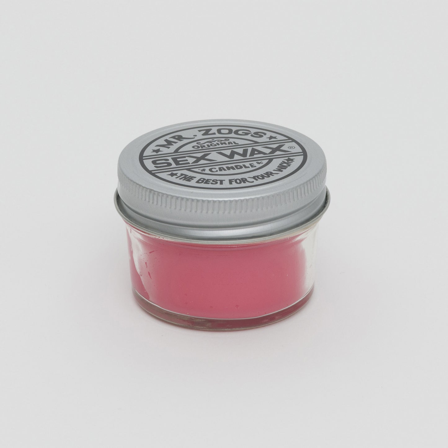 Side shot of pink candle in a glass jar with screw top lid.