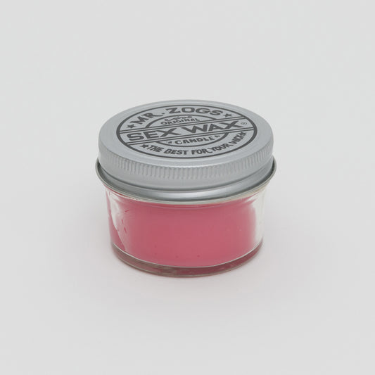 Side shot of pink candle in a glass jar with screw top lid.
