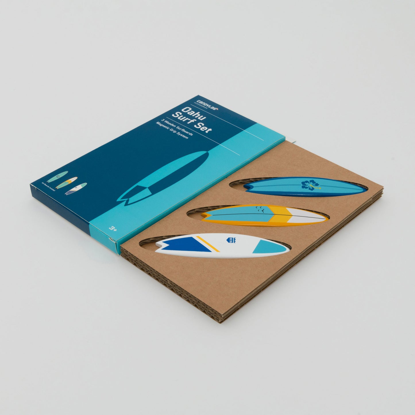 3 wooden surfboard magnets in white yellow and blue shown in cardboard packaging