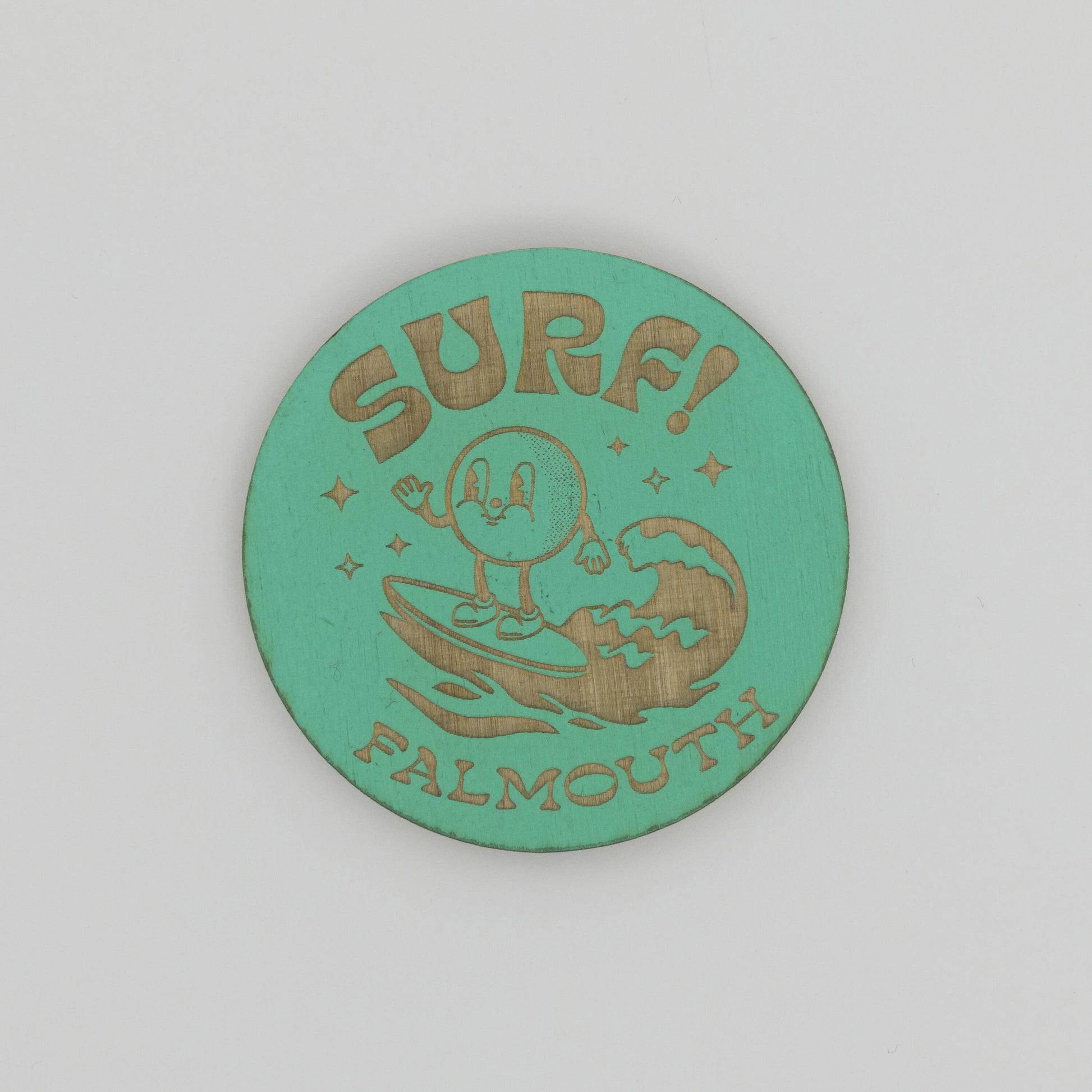 Green, round wooden magnet with character surfing a wave with the words SURF, Falmouth