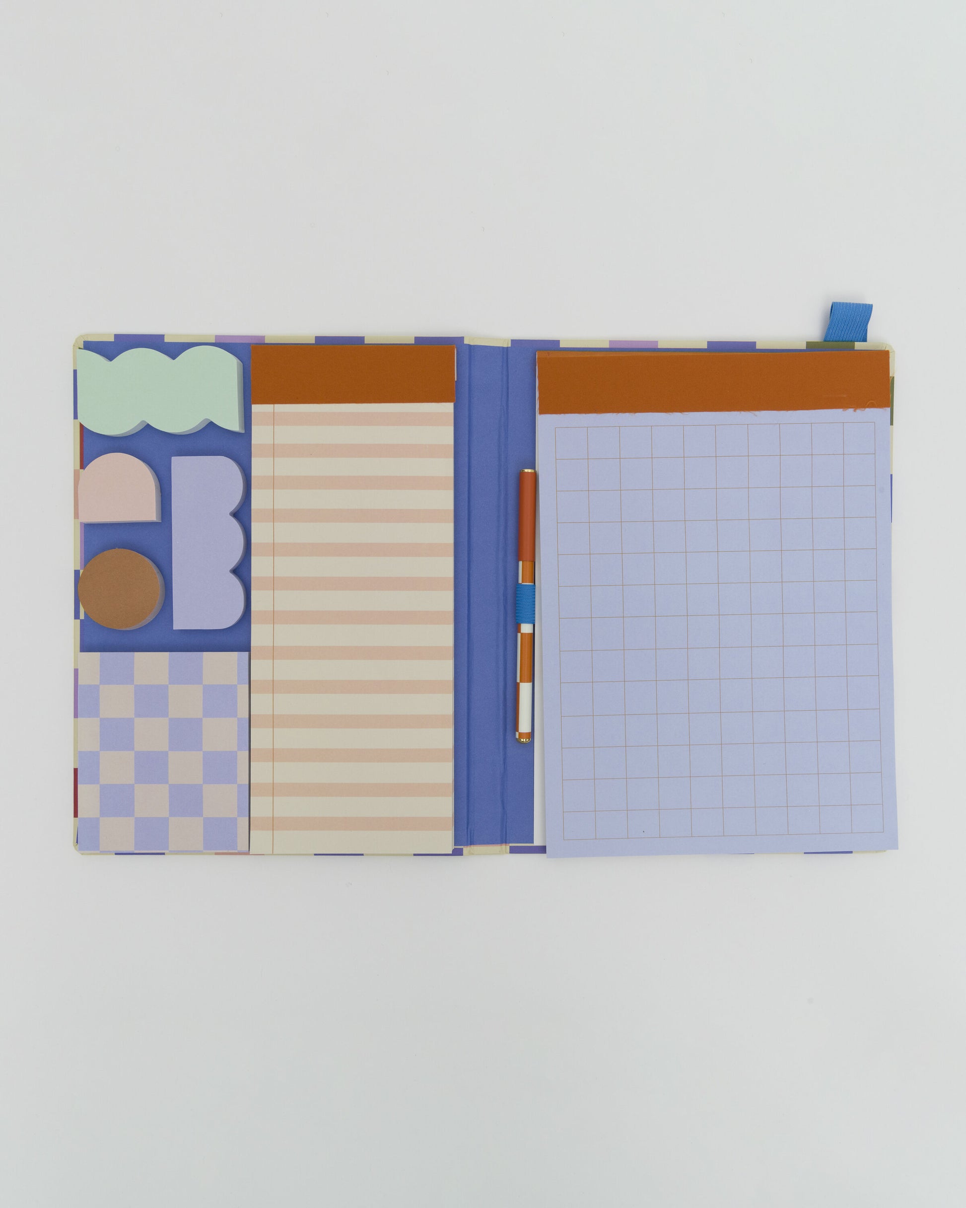 Image of the inside of the notebook, with 4 sticky note pads in quirky shapes, 3 pads to write on and a orange and cream checkerboard pen.