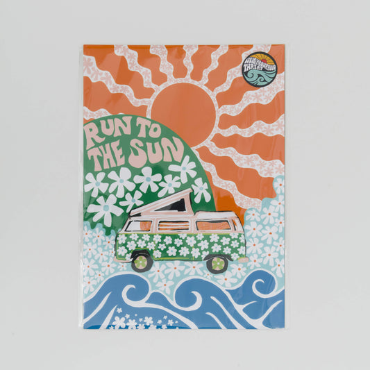 A4 print showing a green camper van covered in white daisies with a green hill in the background with daisies and the wording Run to the Sun in pink font. Big orange sun in the background.