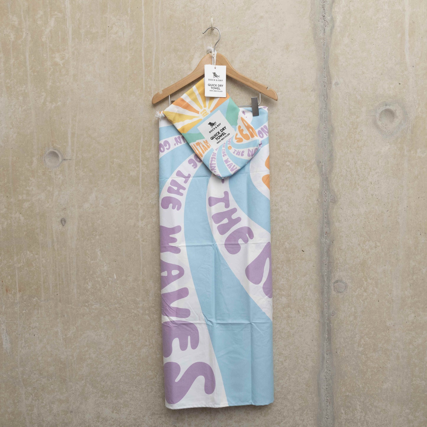 Beach towel, hung on a hanger with the carry pouch hooked onto the hanger