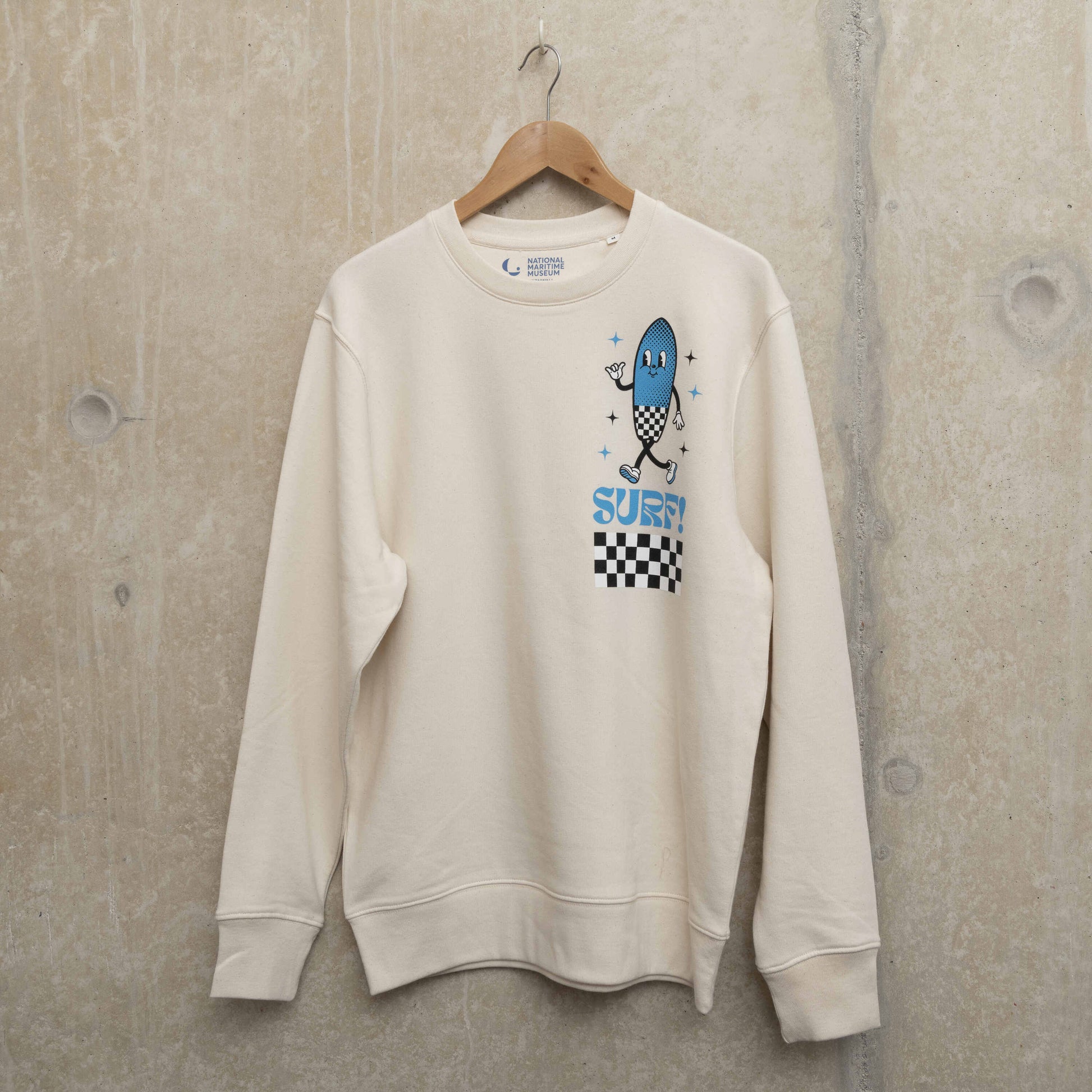 Front shot of cream coloured sweatshirt with surf character on left chest. Character is shaped like a surfboard in blue with black and white checkerboard design, with the word Surf underneath.