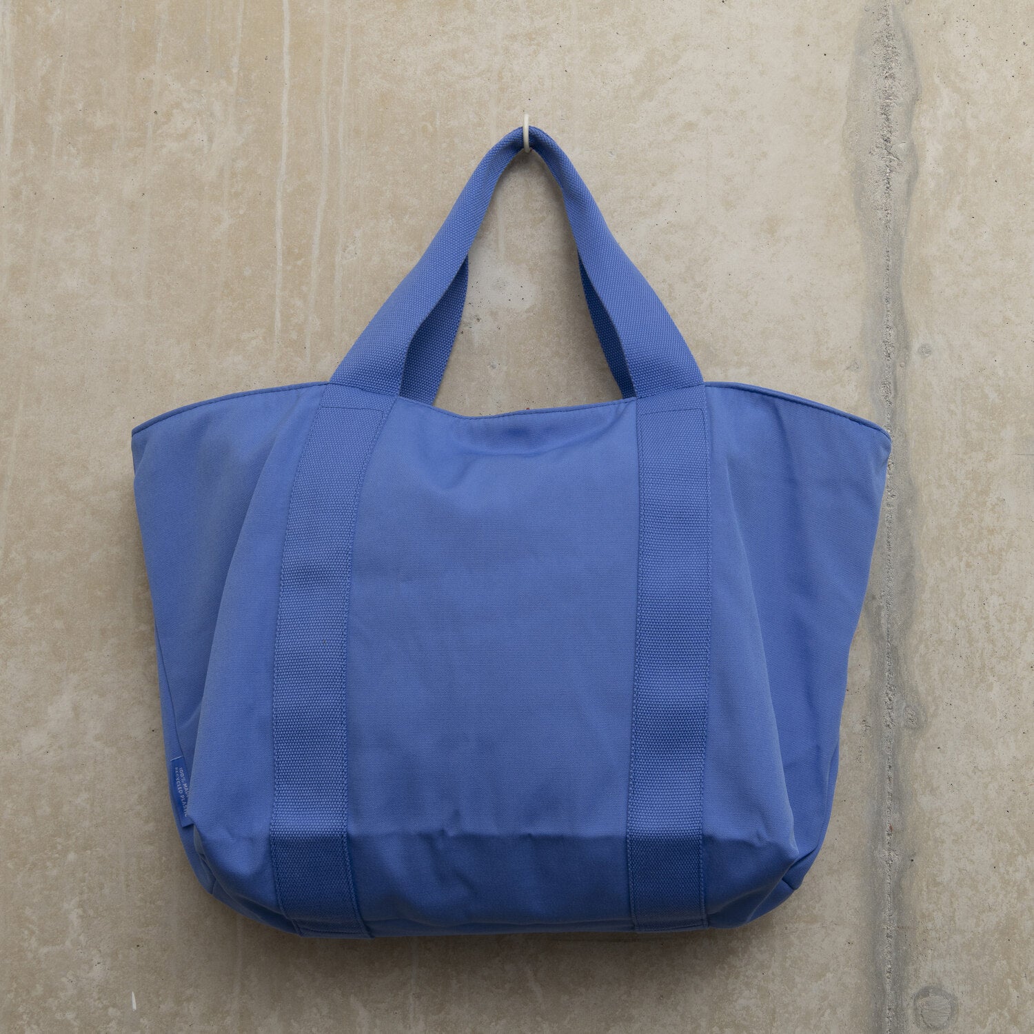 Showing the back of the large light blue tote bag with sturdy handles