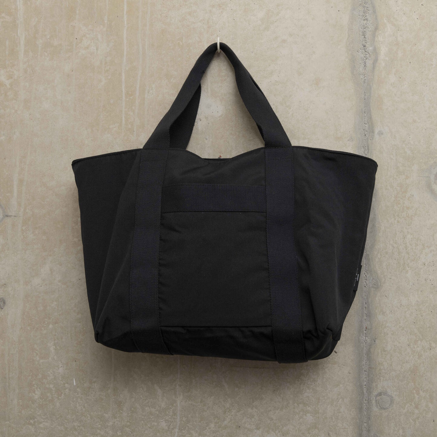 Showing the front of a black tote bag with sturdy handles