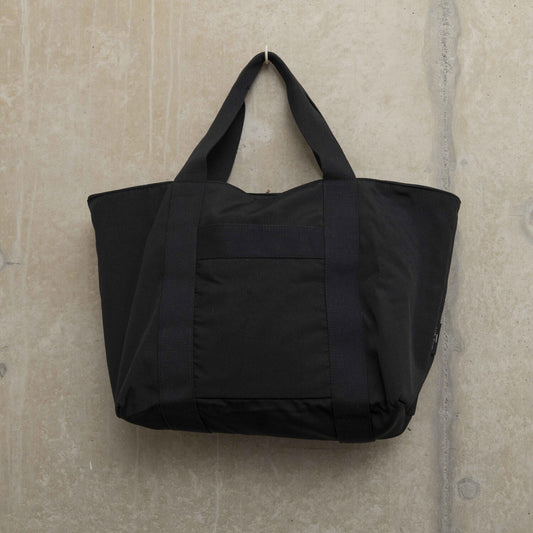 Showing the front of a black tote bag with sturdy handles
