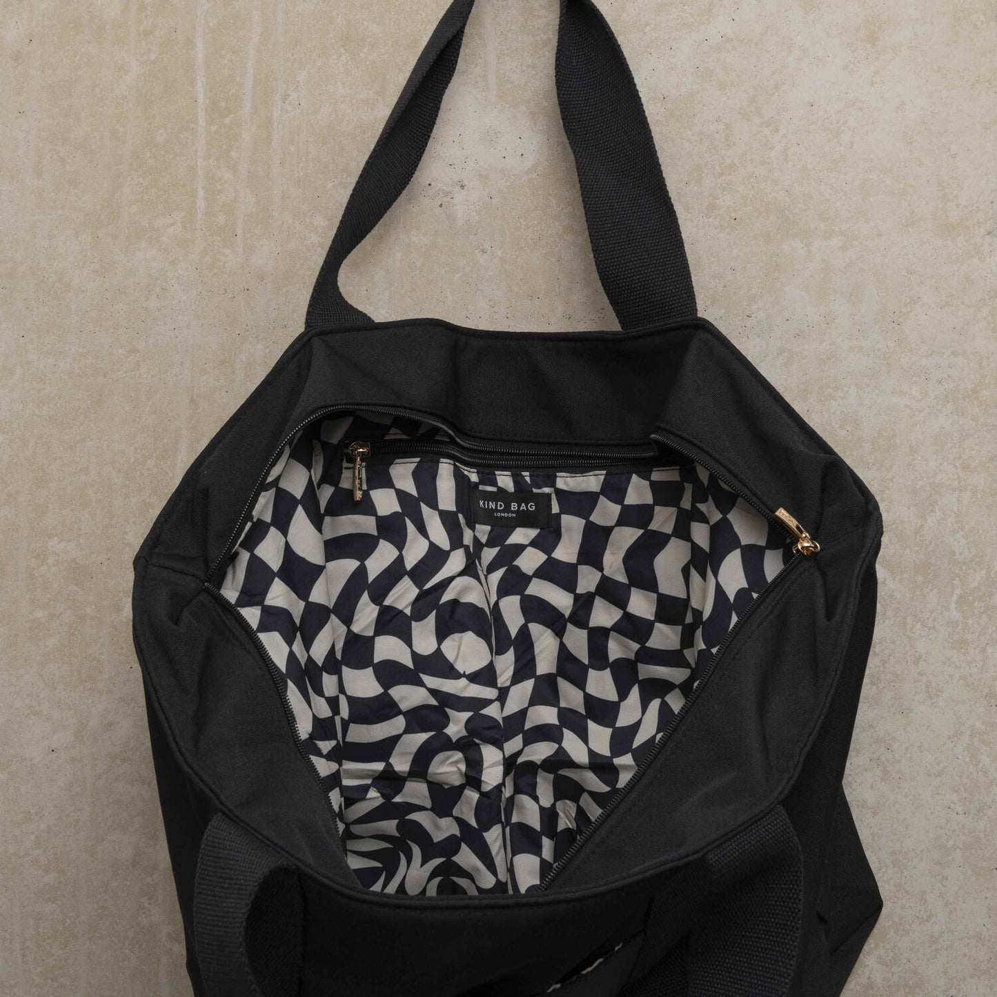 Showing the inside of the black tote bag with black and white wavy checkerboard pattern
