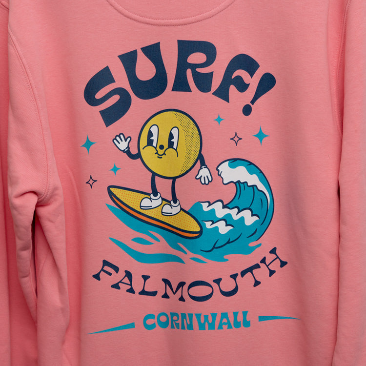 Close up of large surf motif across the back of the sweatshirt. Motif shows round character surfing a wave with the wording SURF! Falmouth, Cornwall.