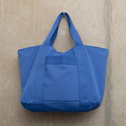 Showing the front of a blue tote bag with sturdy handles
