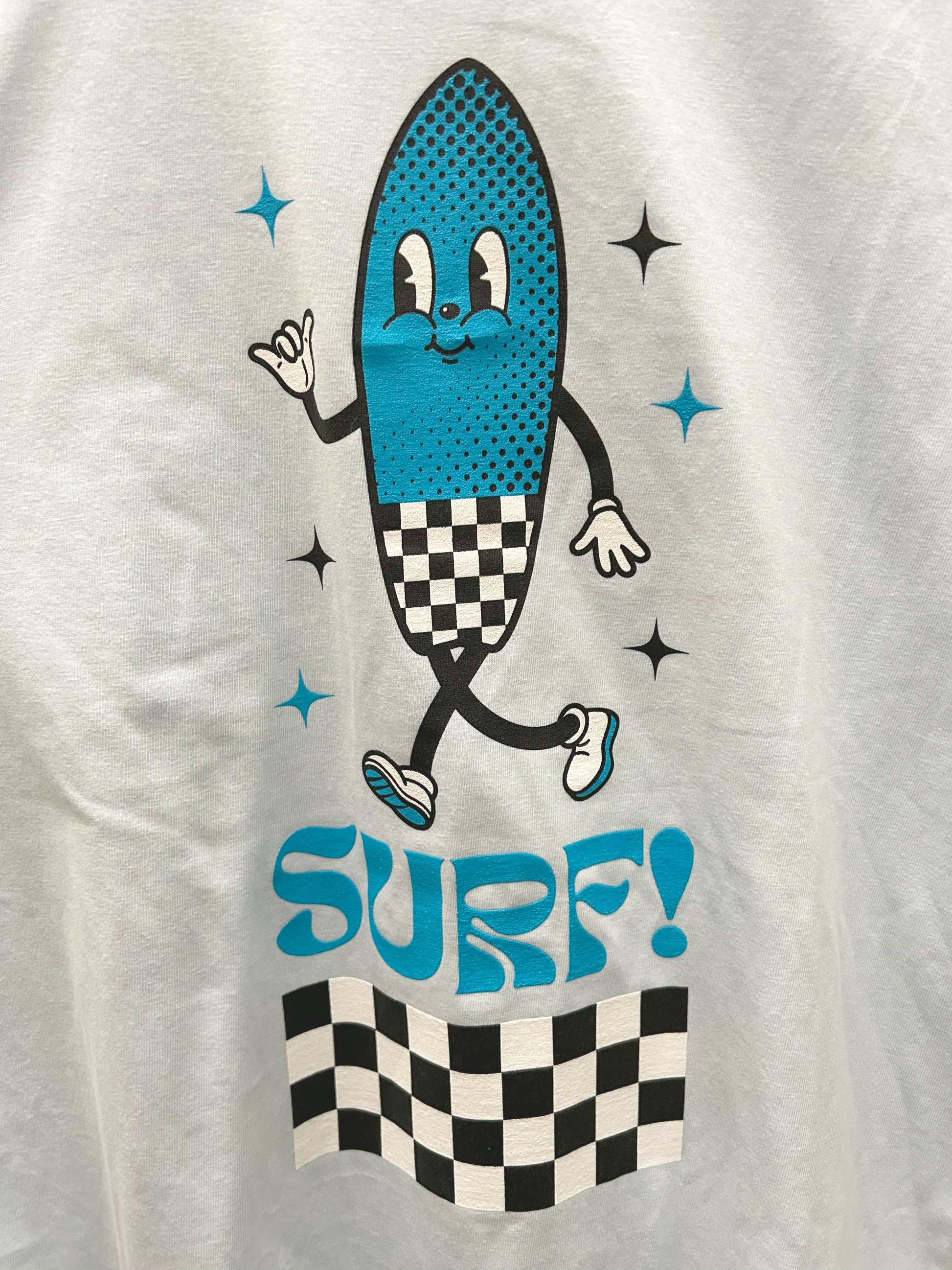 A close-up of a pale blue t-shirt with a smiling surfboard cartoon icon