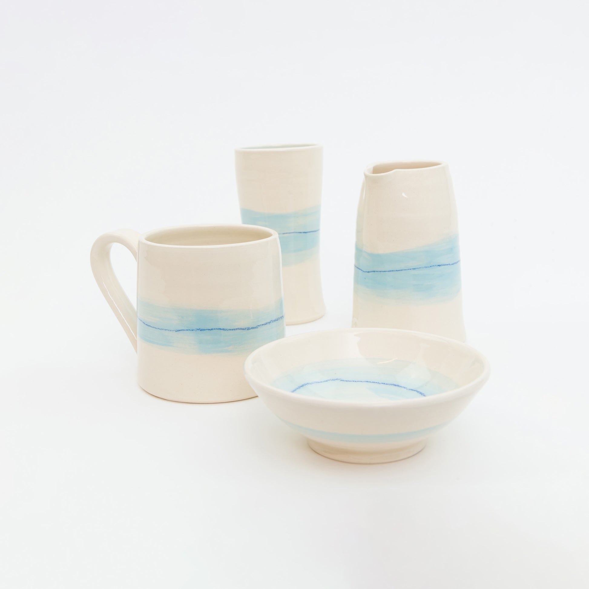Set of ceramic mugs, bowls, and vases with blue and white stripes on a white background