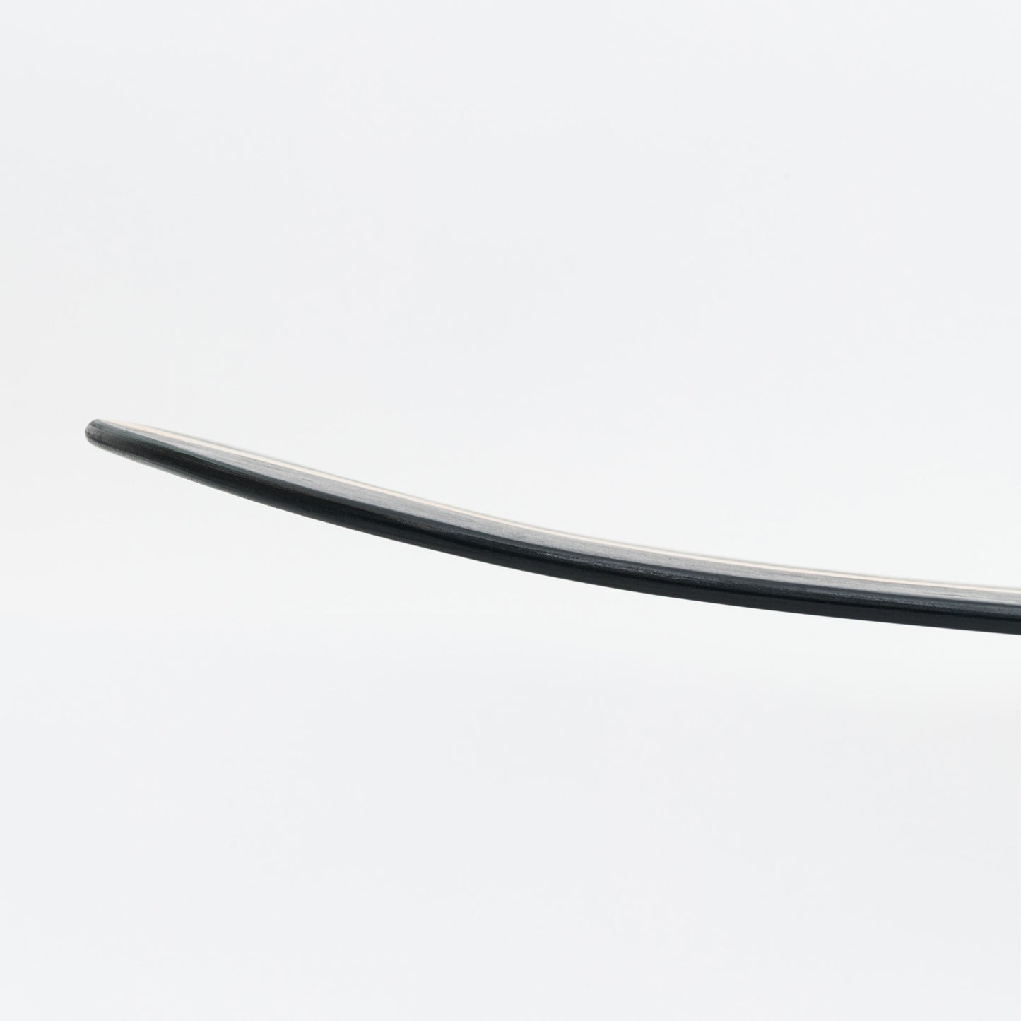 sild shot of curved black wooden bellyboard on a white background