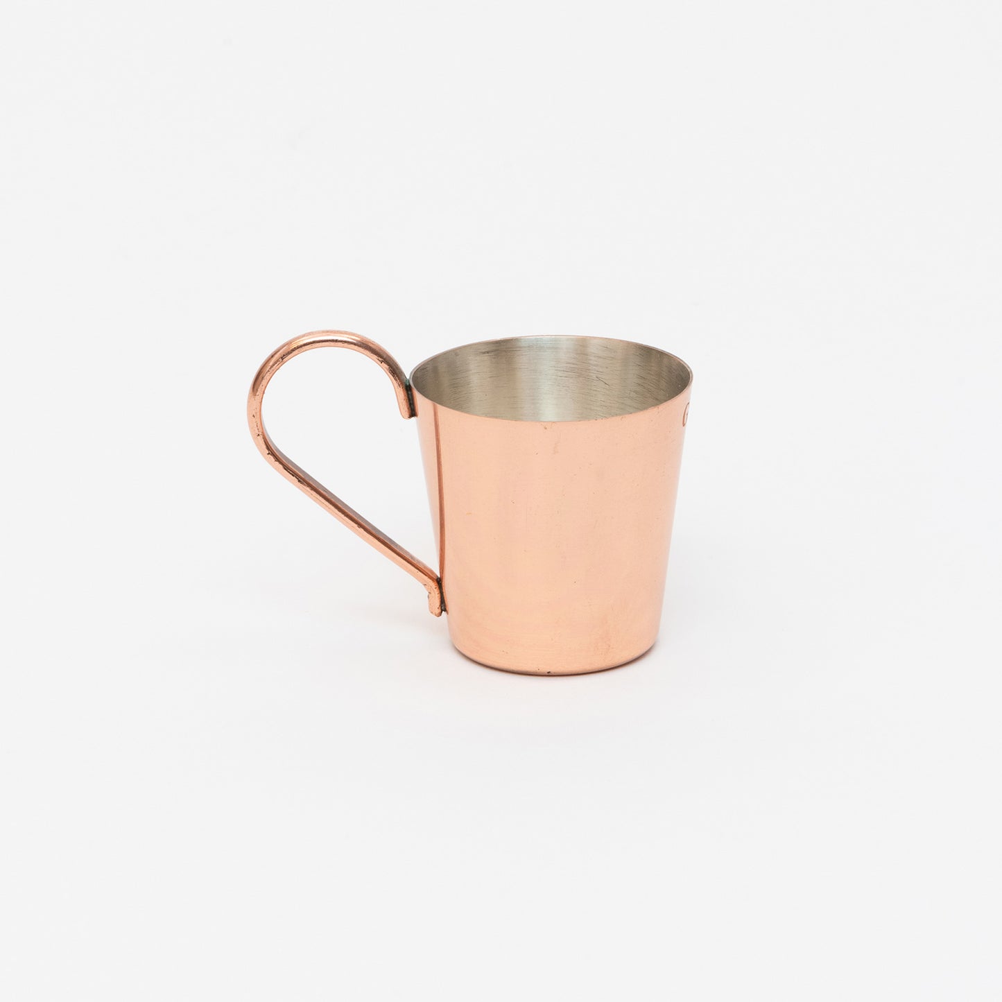 A copper-plated naval rum measure, cup with handle. Pictured on a white background.