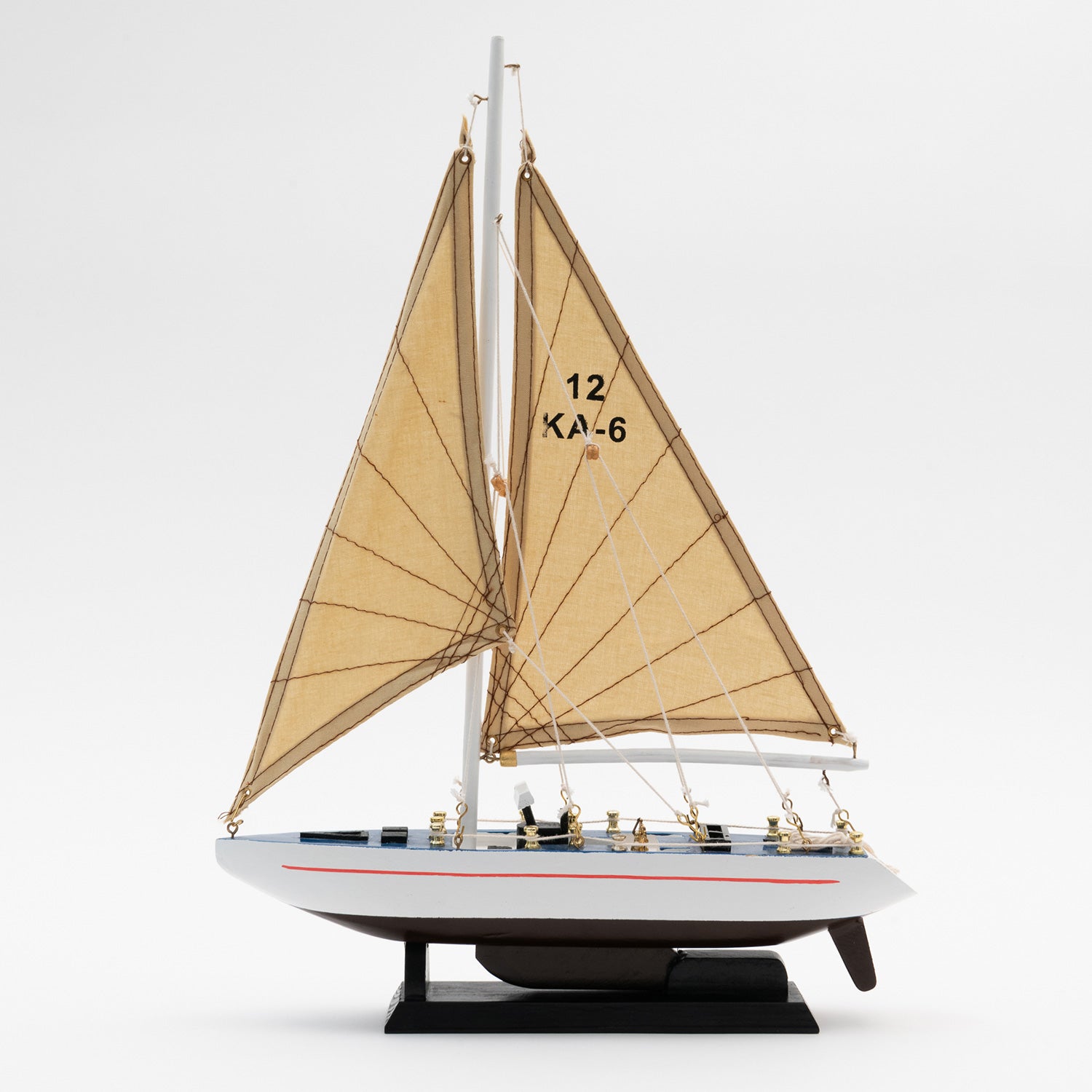 Full view of the side of the model racing yacht with a black and white hull and a tan sails.