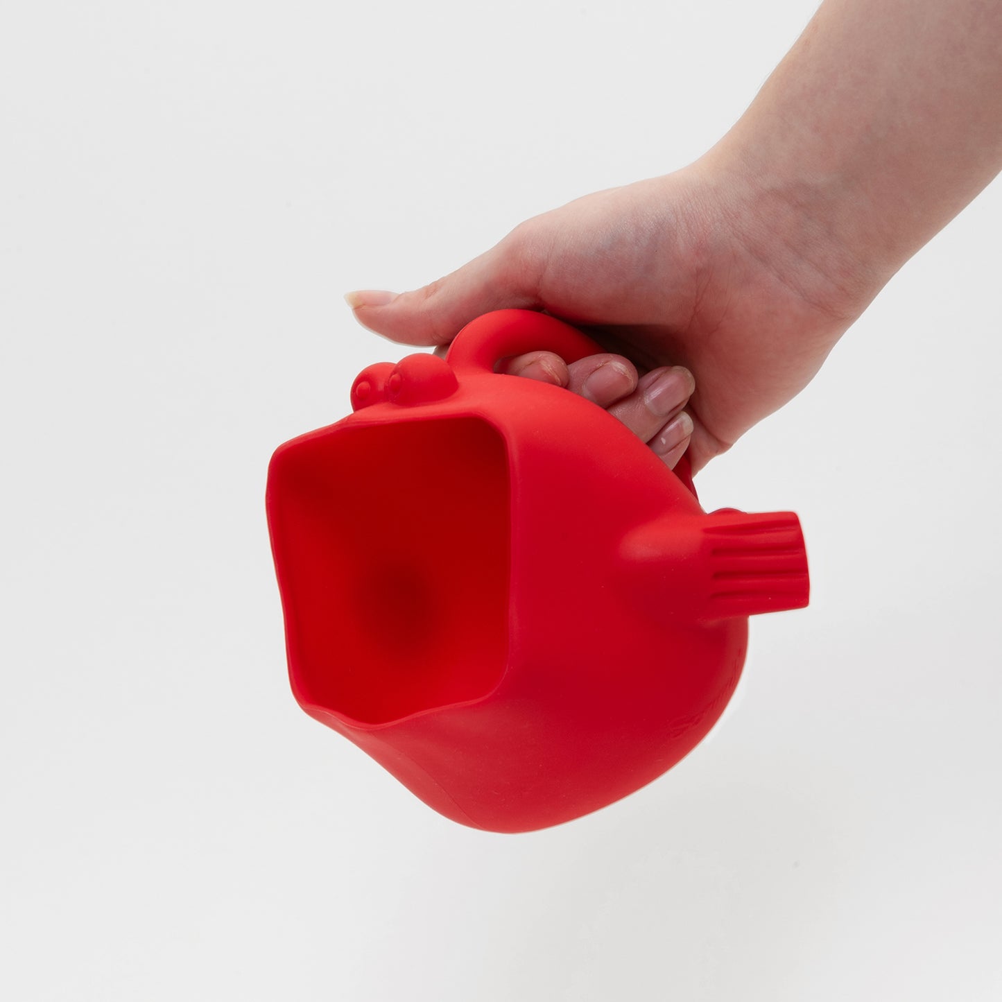 hand holding the handle of red silicone pufferfish with large open mouth to scoop water