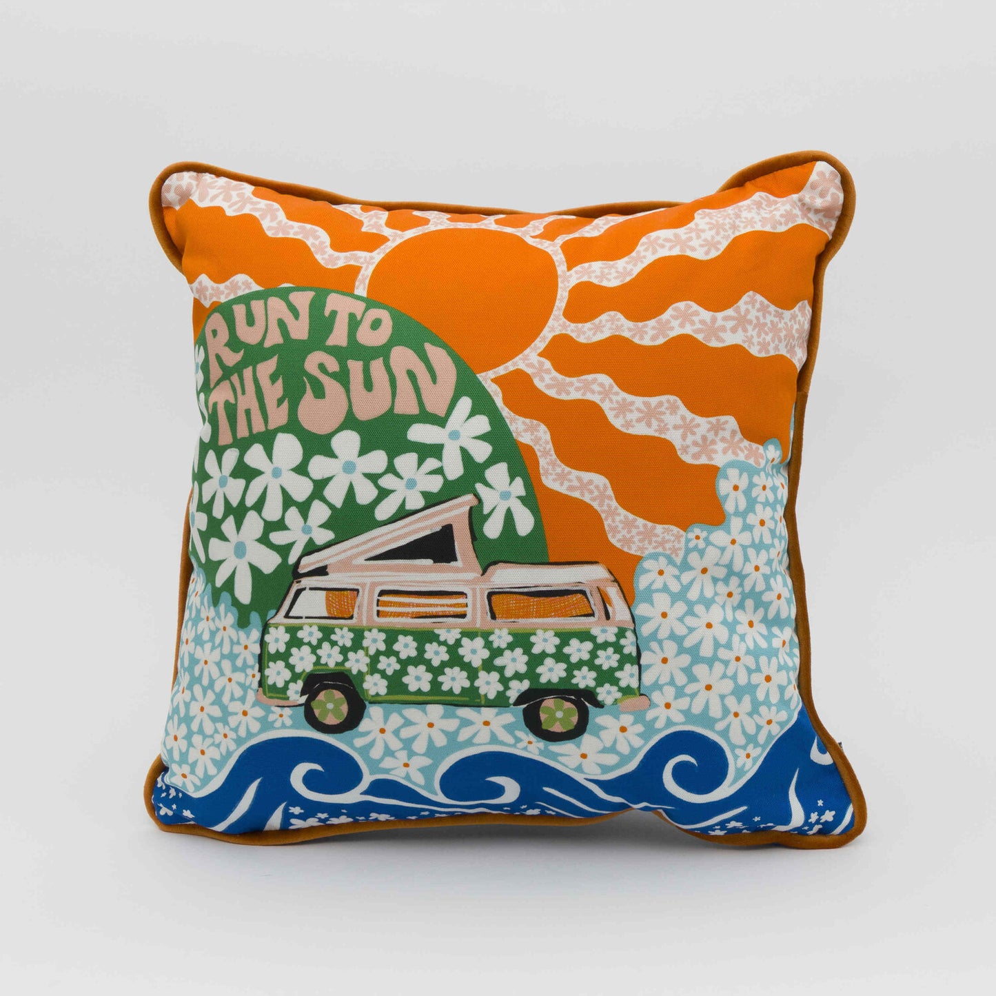 Square cushion showing a green camper van covered in white daisies with a green hill in the background with daisies and the wording Run to the Sun in pink font. Big orange sun in the background.