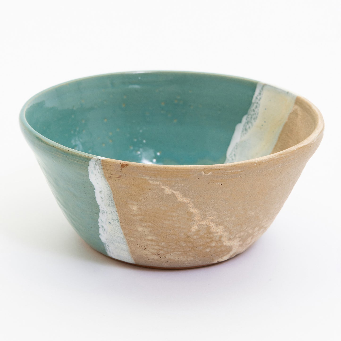 A bowl pictured on a white background. The bowl has an ocean shoreline design, with the sea, a wave, and the sand across it.