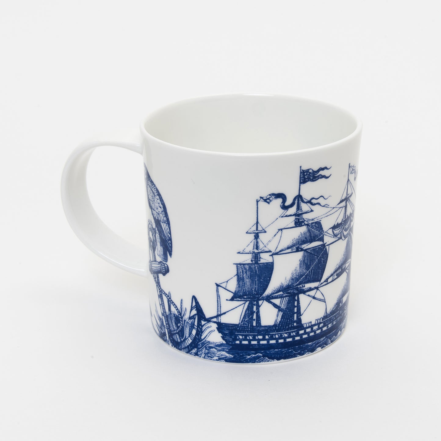 Shot of the other side white mug with blue illustration of a tall ship and anchor.