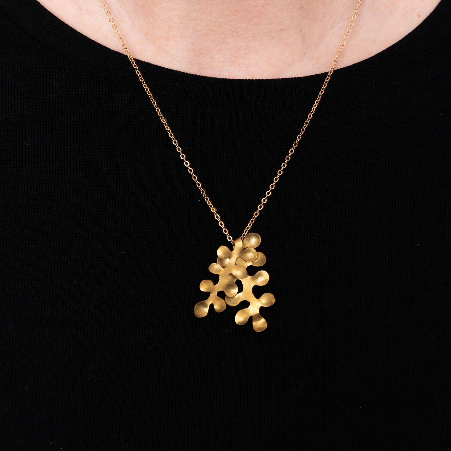 close up of brass bubble pendant against a black t-shirt