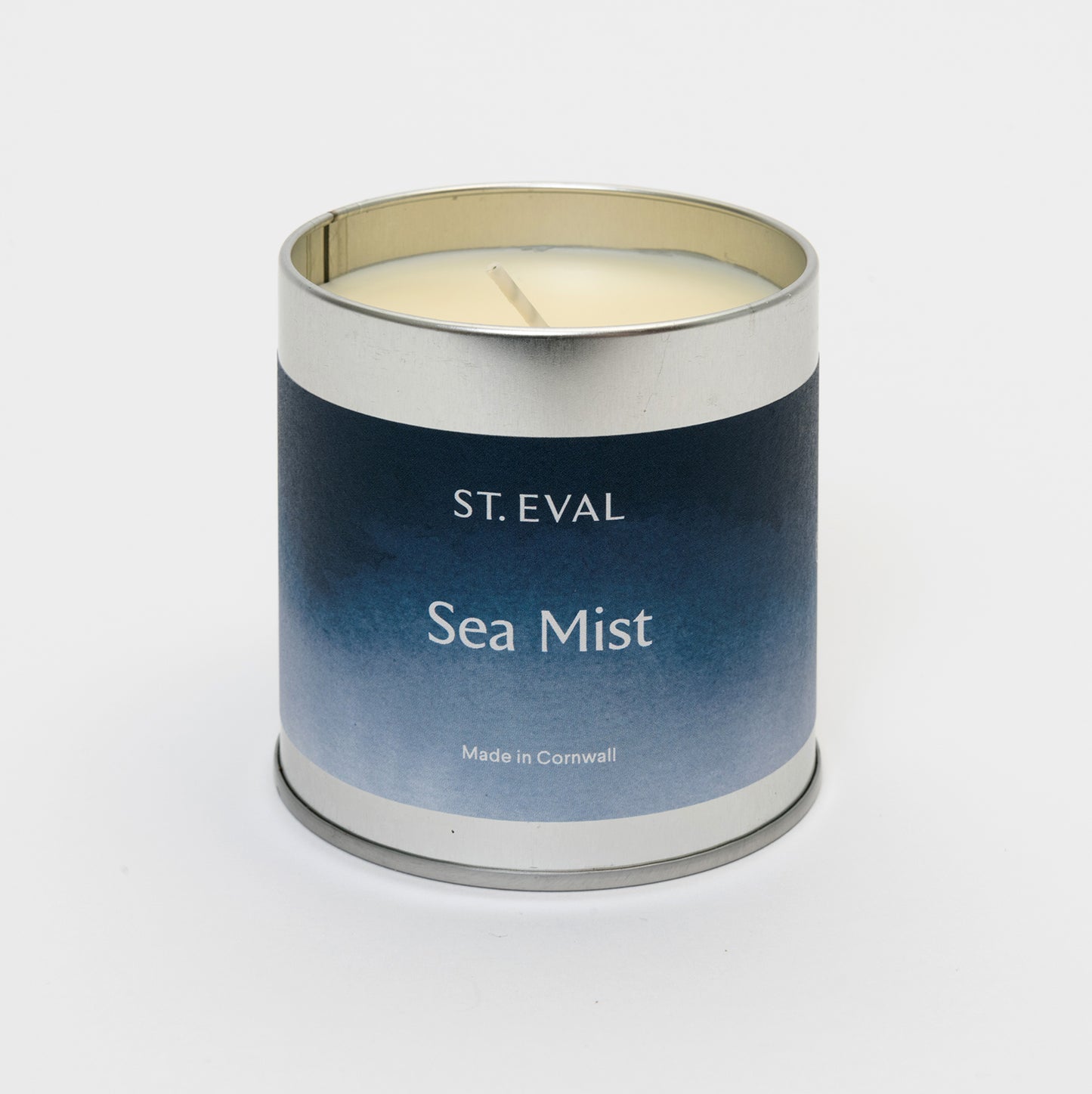 Blue label on a round tin with the lid off showing candle and wick