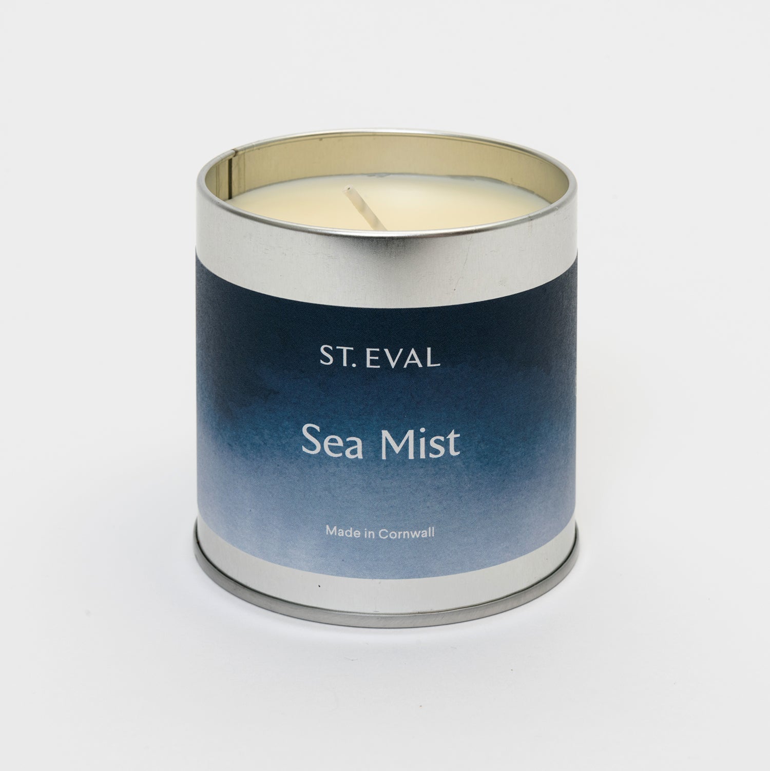 Blue label on a round tin with the lid off showing candle and wick
