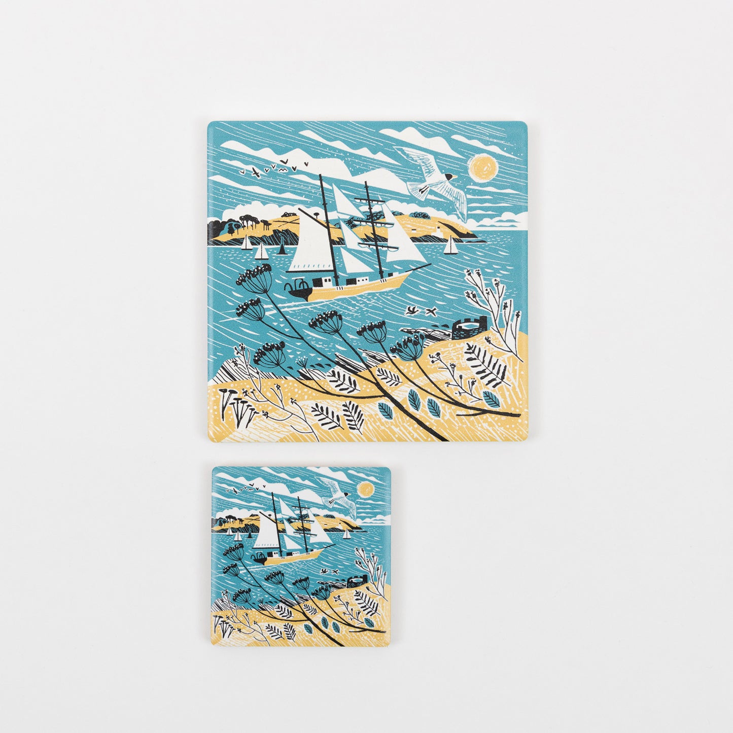 A top down view of the Falmouth Tall Ships Coaster in a yellow, blue and white design featuring a tall ship in full sail. The coaster a displayed alongside the smaller Falmouth Tall Ship magnet.