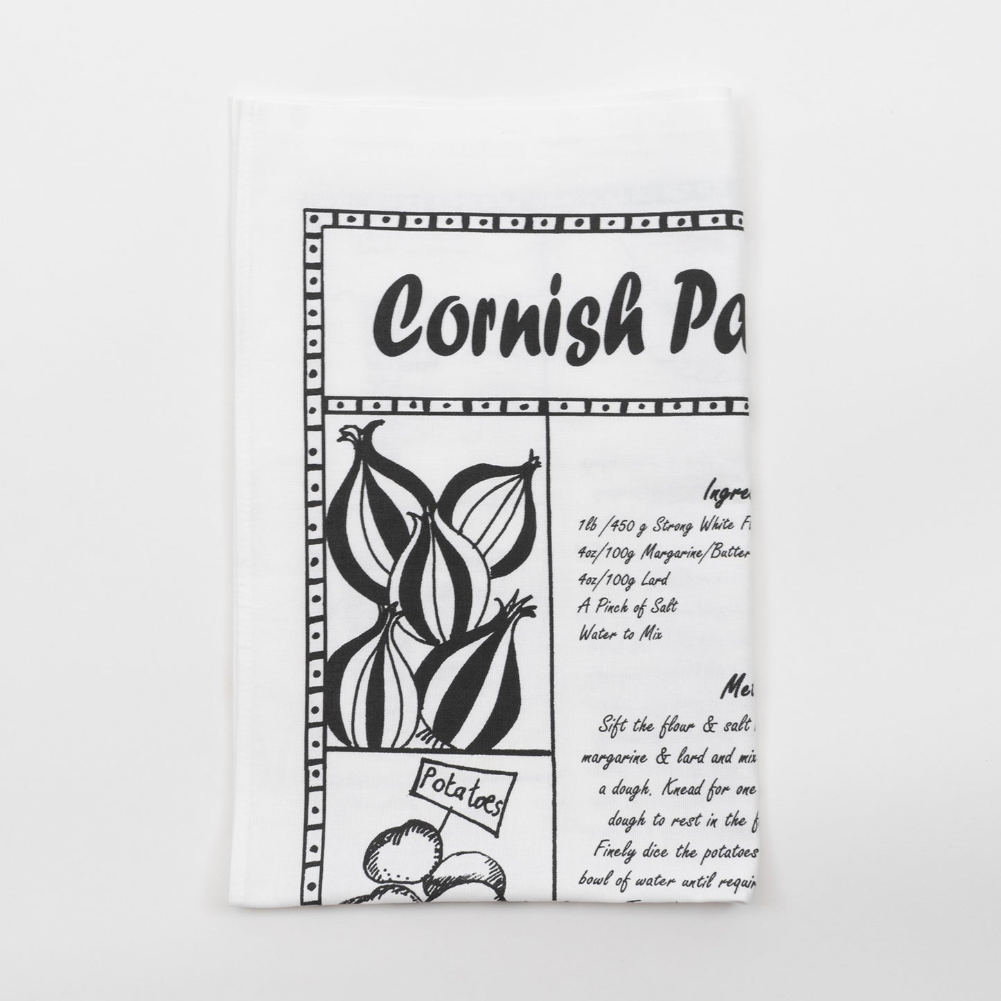 Folded black and white Cornish pasty recipe tea towel against a white background.