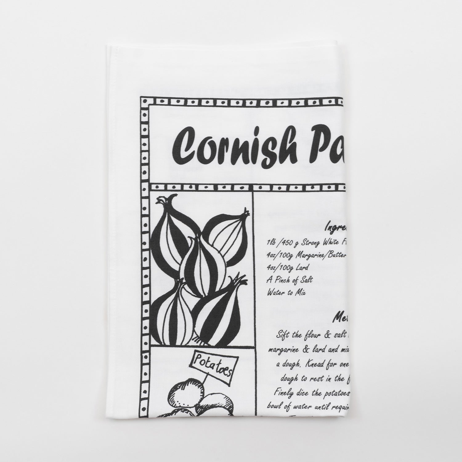 Folded black and white Cornish pasty recipe tea towel against a white background.