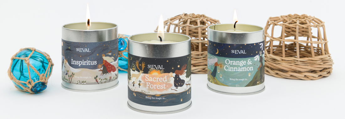 A collection of St Eval Candles in decorative tins displayed with miniature lobster pot and glass buoy decorations.