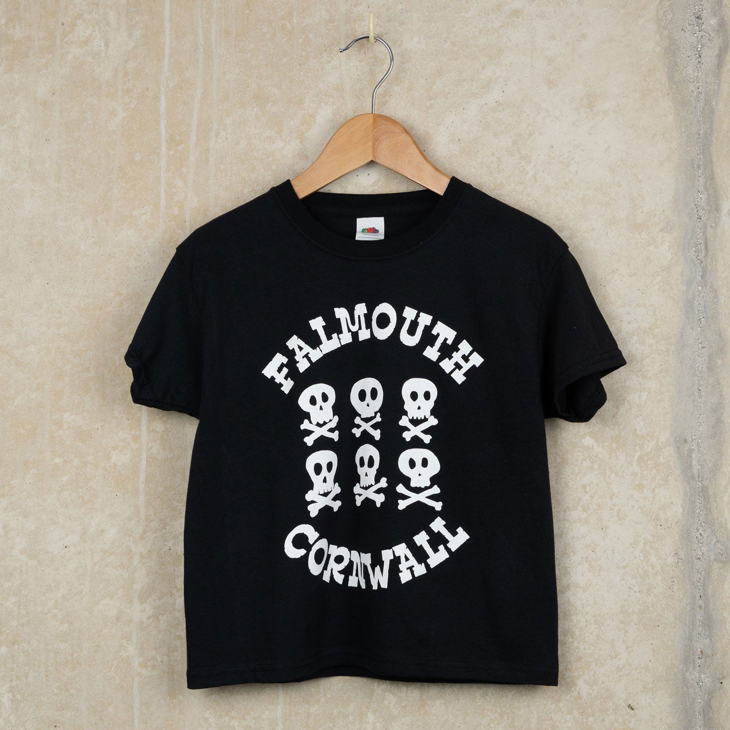 A child's black t-shirt featuring six white skull and crossbones and the words Falmouth Cornwall.
