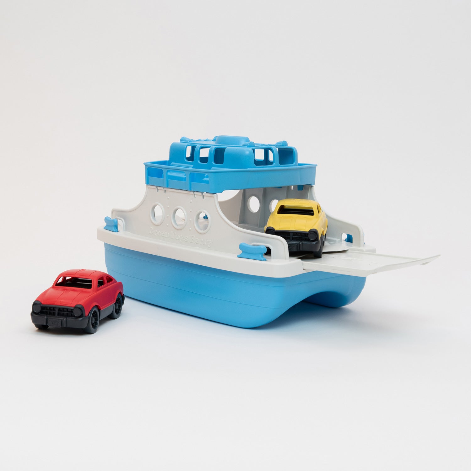 A photo of a toy white and blue ferry with yellow and red cars, pictured on a white background.