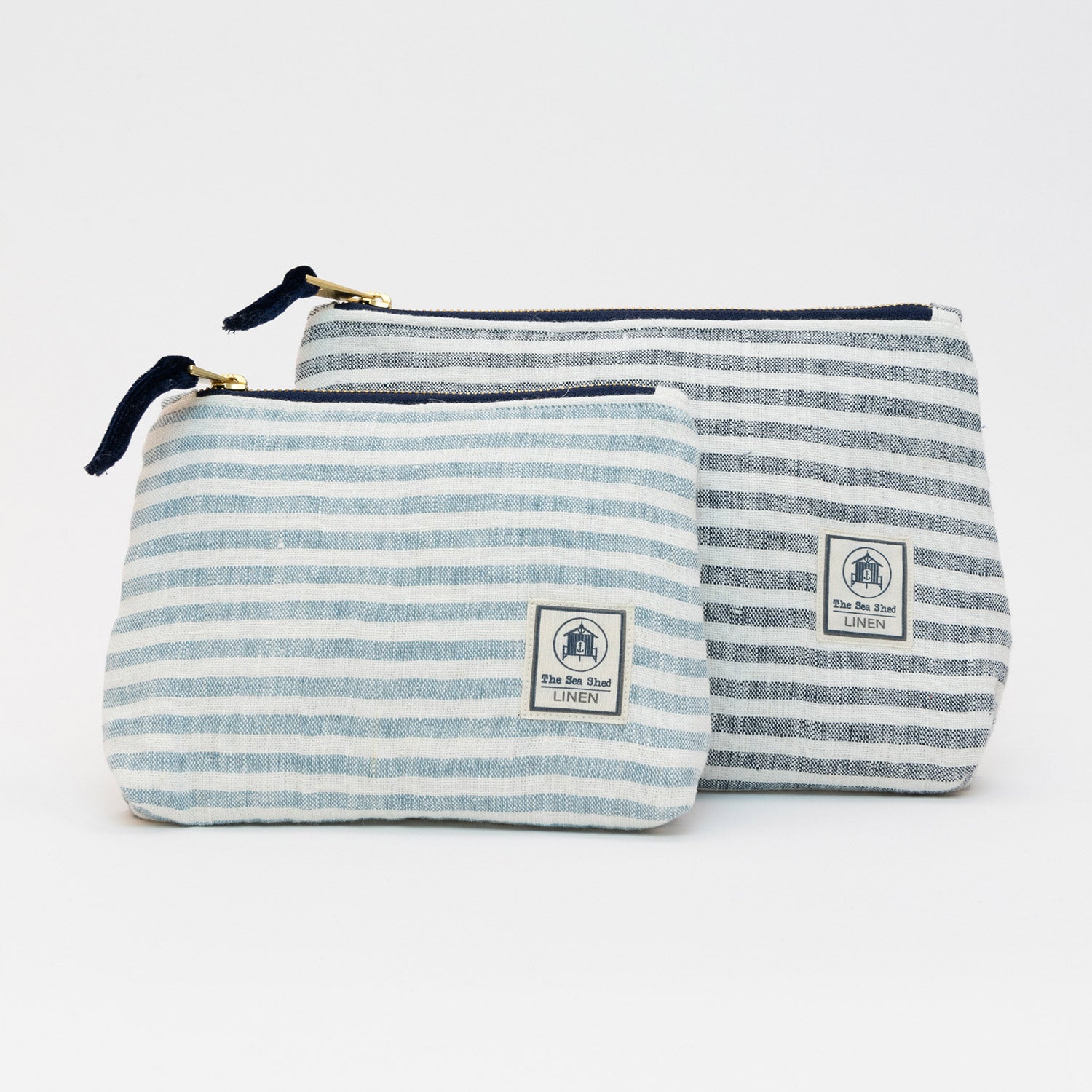 Two linen cosmetic bags pictured on a white background. They both have blue and white stripes.